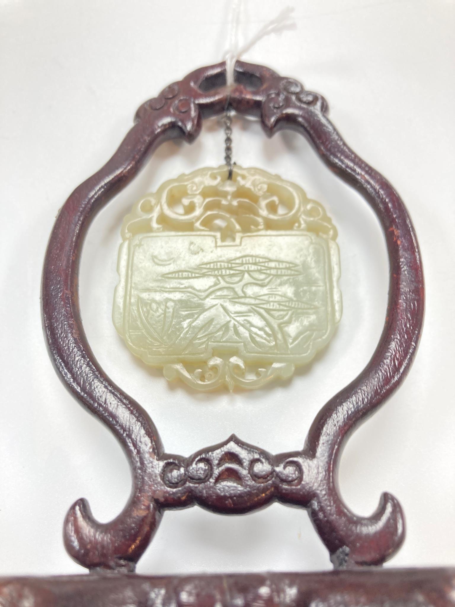A Chinese pale celadon jade inscribed plaque, 19th/20th century, 5.1cm, suspended from a wood stand